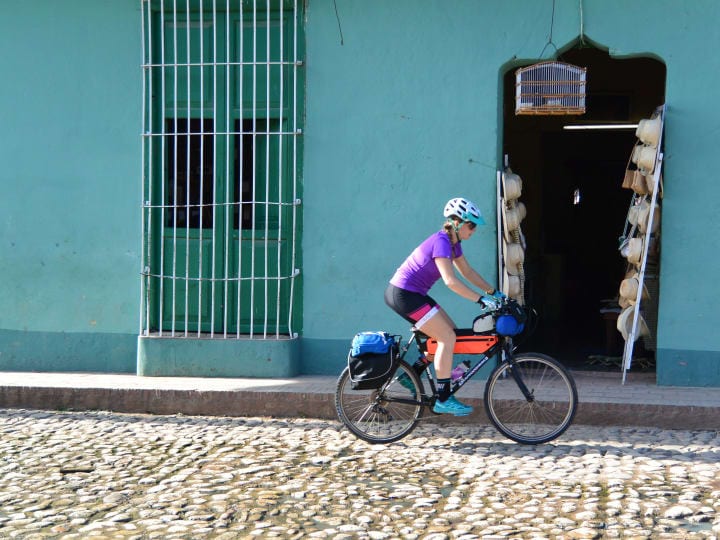 Woman biking on cobblestone street in Cuba