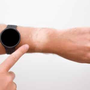 Man finger pointing to not tanned skin from black smart watch. Gray background. Problem of daily using watch in summer time. Closeup.